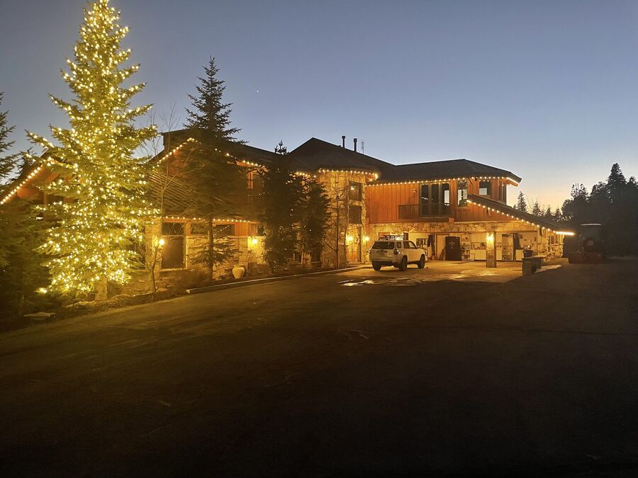 A lodge at dusk, its tallest spruce lit top to bottom