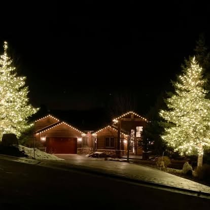 Home with warm white holiday lights on the roofline and trees